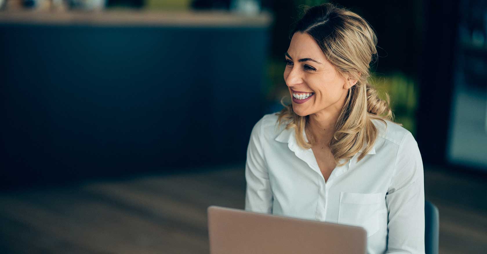 Photo of a woman smiling in front of her laptop